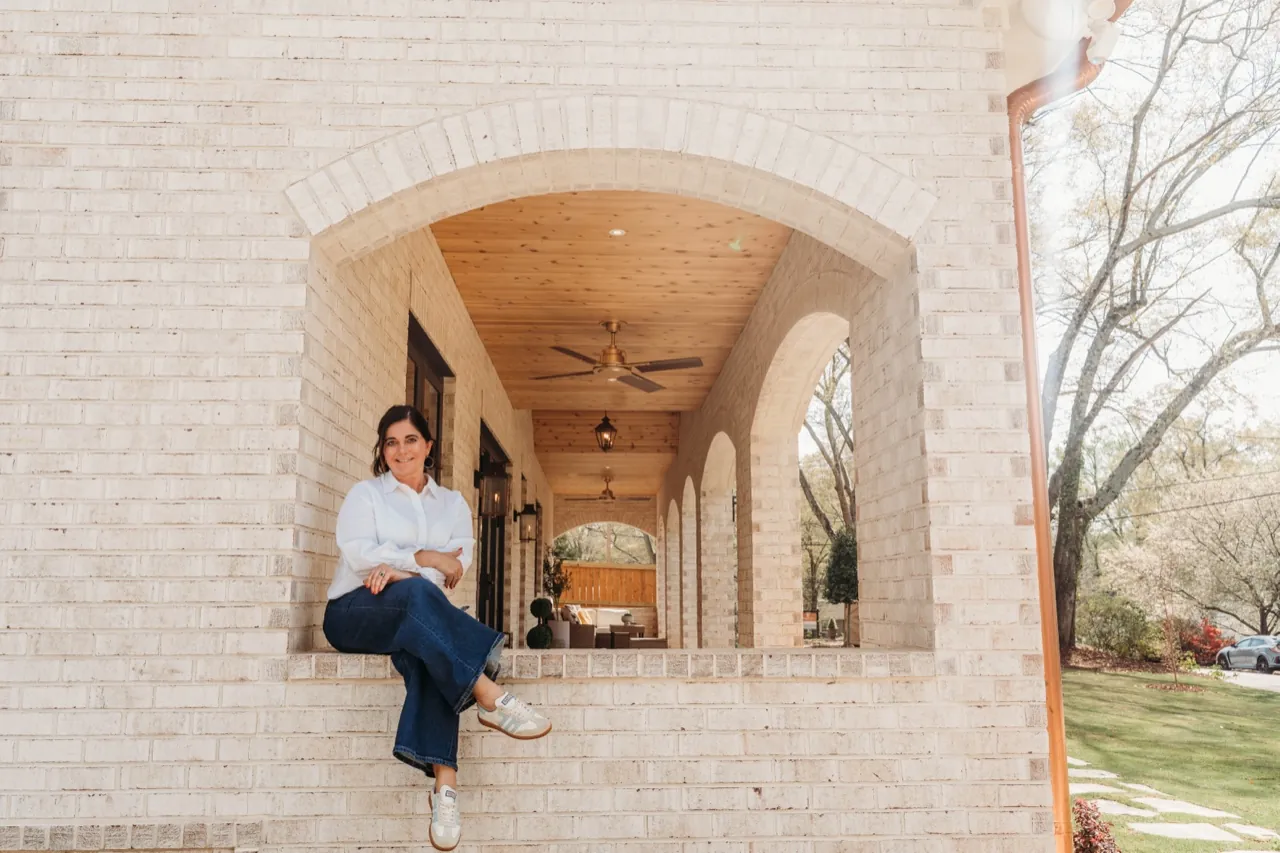 Danielle Wilkinson, founder of Cotswold House Co., on the brick-arched porch of a home she designed in Greenville, South Carolina