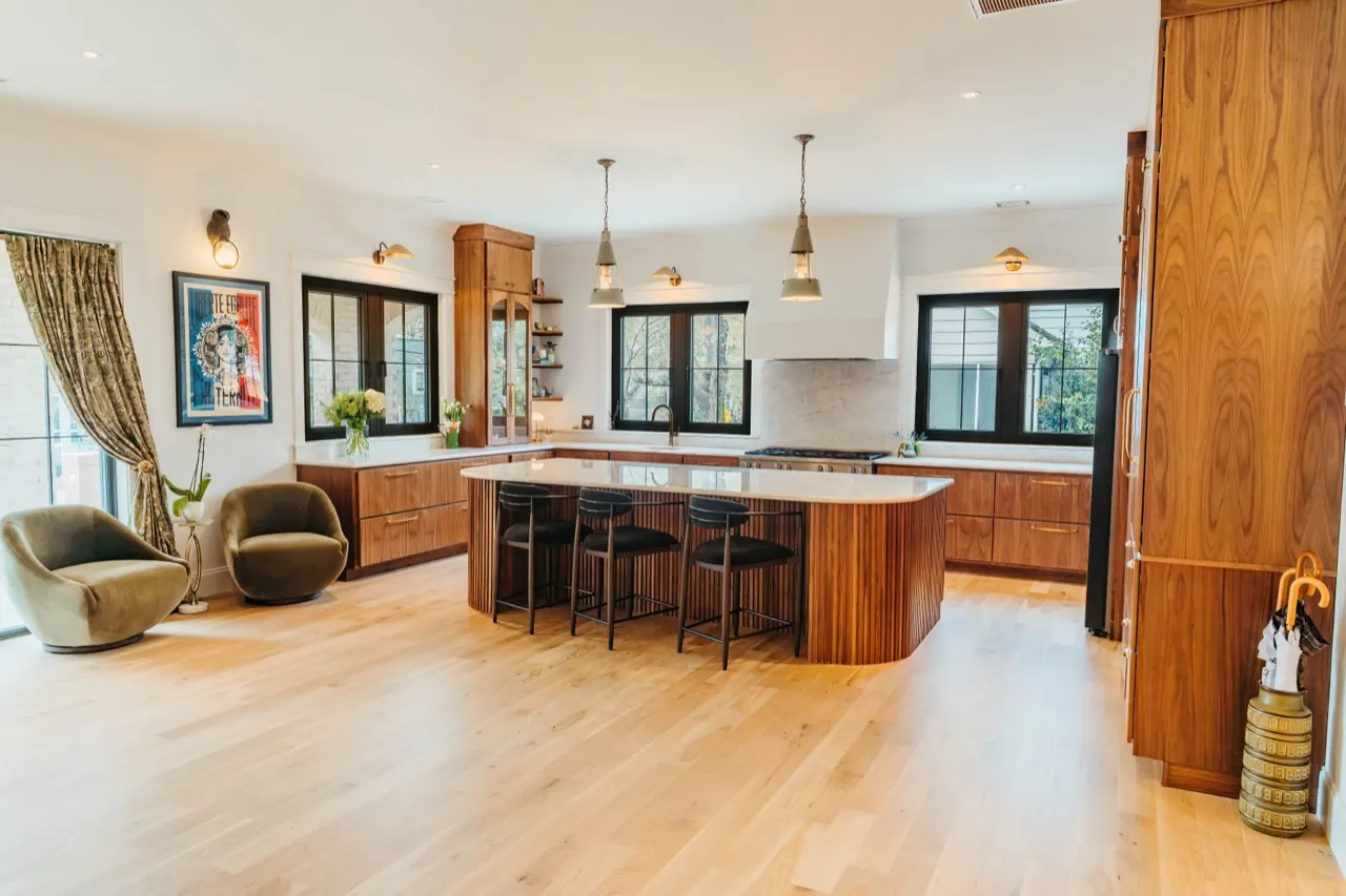 Open-plan kitchen we designed in Greenville — walnut cabinetry, layered pendant lighting, considered finishes